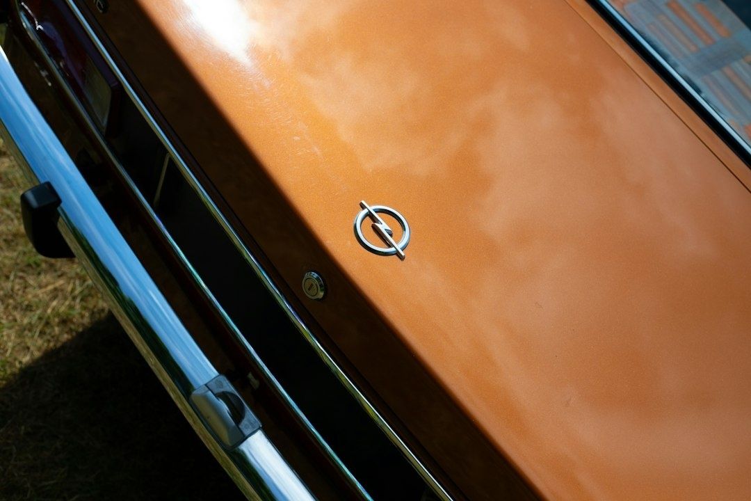 Nahaufnahme des Opel-Emblems auf einer glänzend orangefarbenen Motorhaube